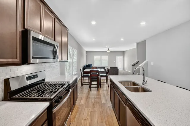 a kitchen with stainless steel appliances granite countertop a stove a sink and a microwave