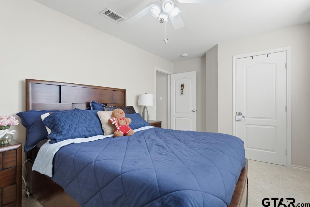 5821 Thompson Place Tyler, TX 75707 - Photo 27 of 34 a bedroom with a large bed and a chandelier