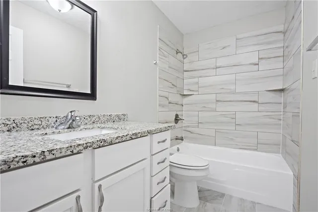 a bathroom with a granite countertop toilet a sink and a bathtub
