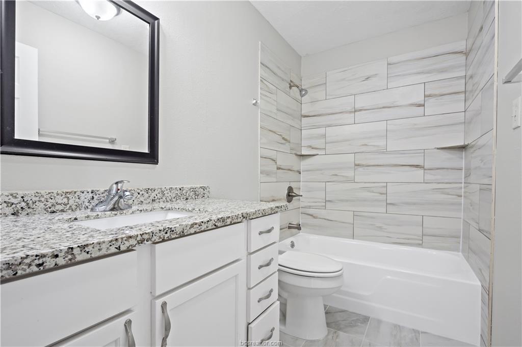 1907 Orman Street Bryan, TX 77801 - Photo 12 of 20 a bathroom with a granite countertop toilet a sink and a bathtub