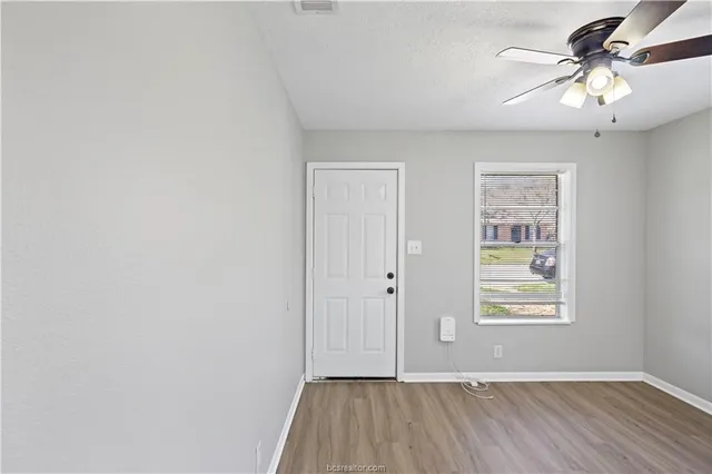 an empty room with windows and fan