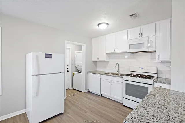 a kitchen with a refrigerator a stove top oven and white cabinets