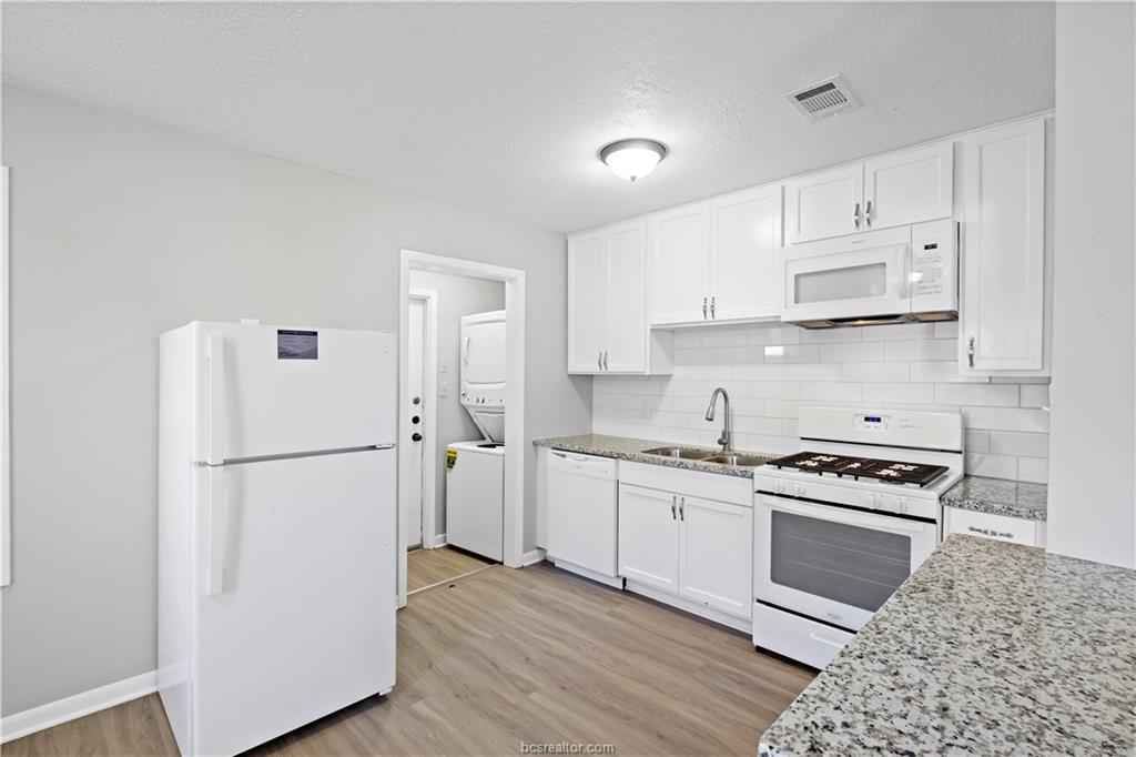 1907 Orman Street Bryan, TX 77801 - Photo 7 of 20 a kitchen with a refrigerator a stove top oven and white cabinets
