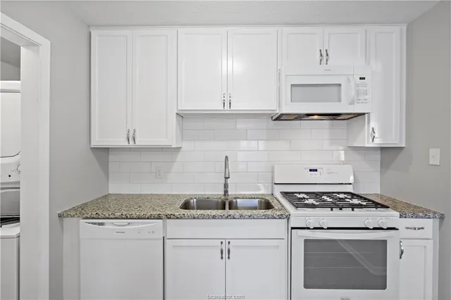 a kitchen with granite countertop white cabinets and white stove