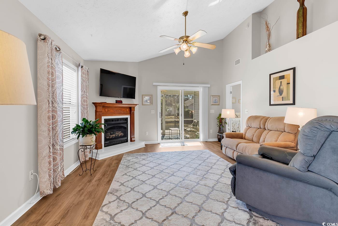 653 Pamlico Court Myrtle Beach, SC 29588 - Photo 11 of 39 Living room featuring light wood-type flooring, a glass covered fireplace, ceiling fan, and high vaulted ceiling