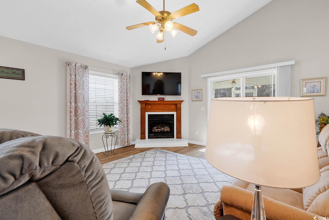 653 Pamlico Court Myrtle Beach, SC 29588 - Photo 12 of 39 Living room with lofted ceiling, wood finished floors, a fireplace with raised hearth, and ceiling fan