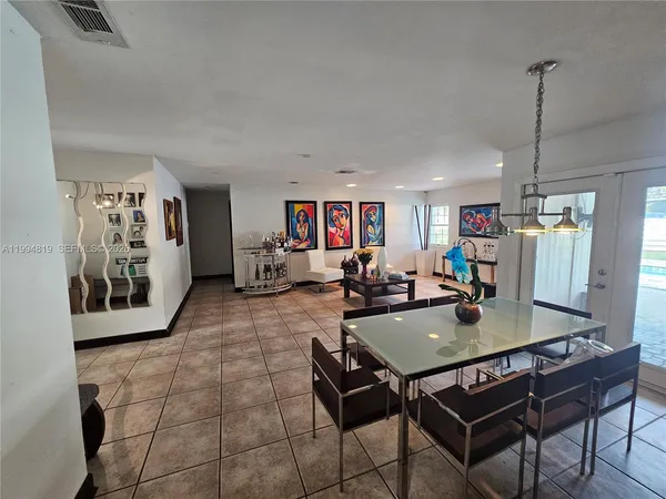 a view of a dining room and livingroom with furniture wooden floor a rug a painting and a chandelier