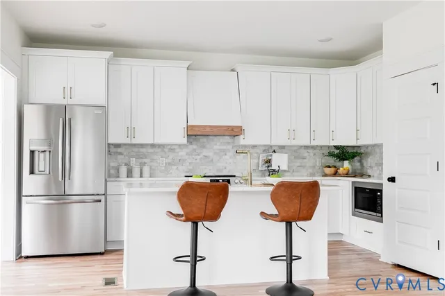 a kitchen with stainless steel appliances granite countertop a refrigerator a stove a sink and white cabinets