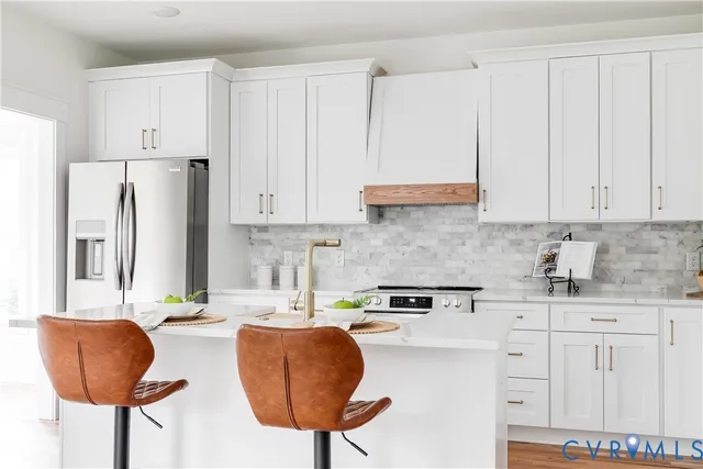 a kitchen with stainless steel appliances granite countertop a sink a refrigerator and a white cabinets
