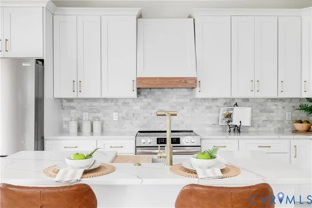 a kitchen with stainless steel appliances granite countertop a sink a stove and white cabinets