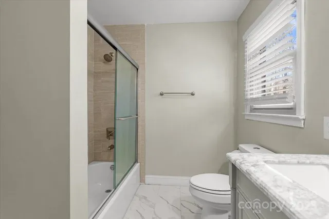 a bathroom with a granite countertop toilet a sink and shower