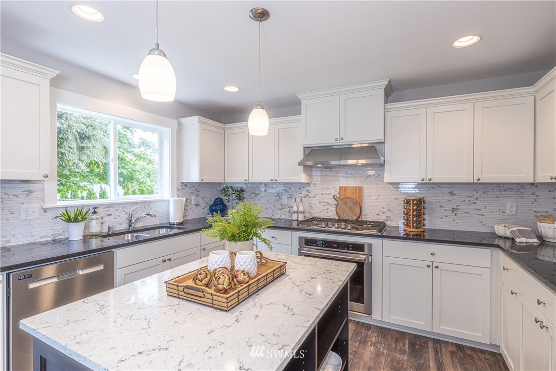613 Index Avenue Northeast Renton, WA 98056 - Photo 9 of 32 a kitchen with kitchen island granite countertop a stove a sink and white cabinets
