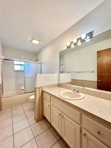 a spacious bathroom with a granite countertop sink a toilet a mirror and shower