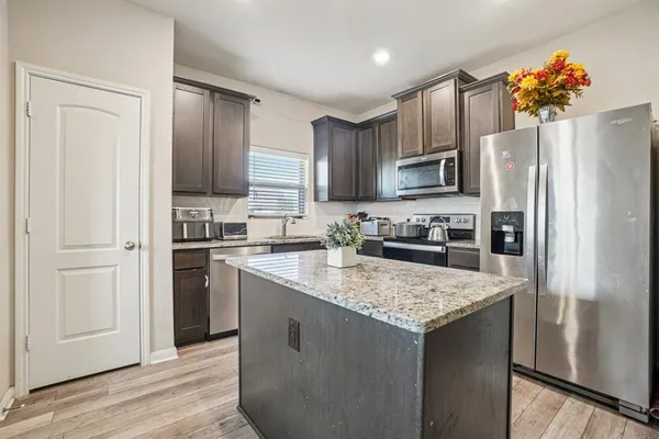 a kitchen with kitchen island granite countertop a refrigerator stove and sink