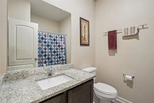 a bathroom with a granite countertop sink a toilet and a shower
