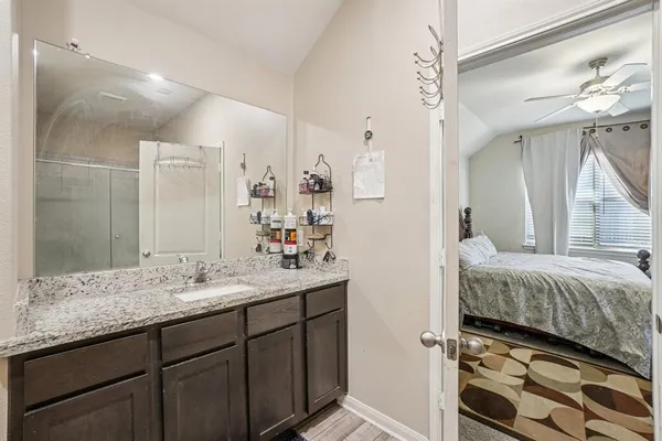 a en suite bathroom with a granite countertop sink and a mirror