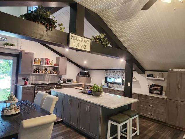 a kitchen with stainless steel appliances kitchen island granite countertop a table chairs and a refrigerator