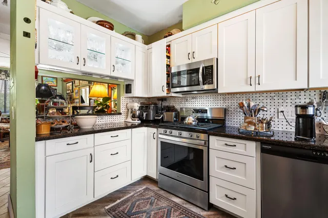 a kitchen with stainless steel appliances granite countertop white cabinets a sink and dishwasher