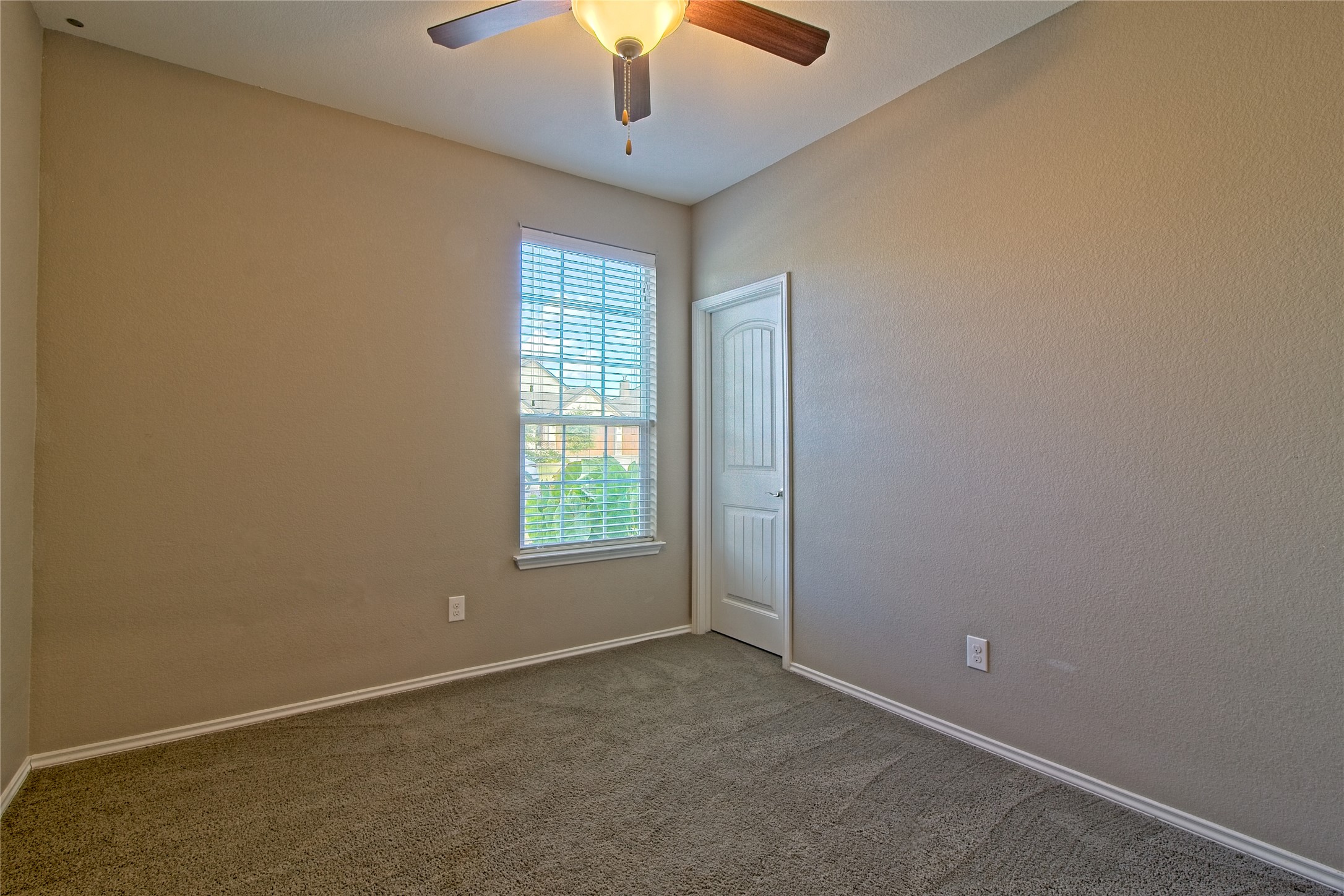 31443 Kingsway Road Georgetown, TX 78628 - Photo 20 of 40 A well-lit bedroom with soft carpet flooring, a window, and a ceiling fan.
