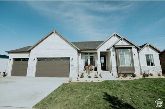 Modern inspired farmhouse with board and batten siding, an attached garage, concrete driveway, and a front yard