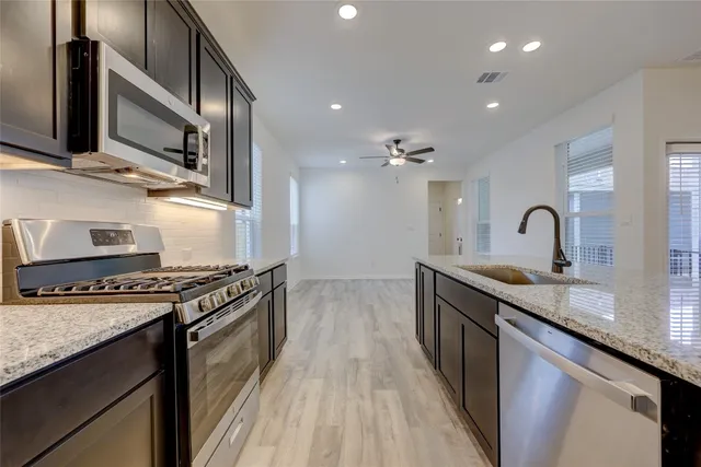 a kitchen with kitchen island granite countertop stainless steel appliances and sink