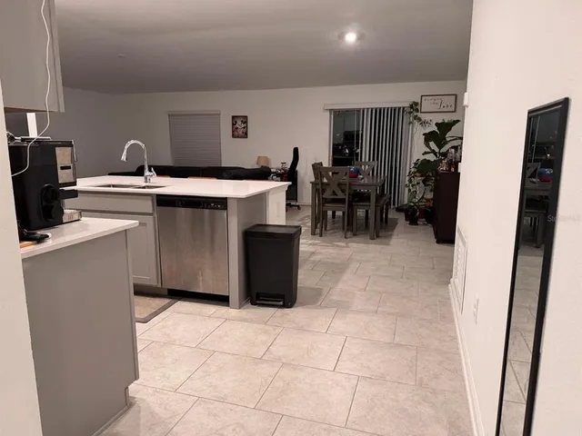 a kitchen with stainless steel appliances a sink a counter top space cabinets and a view of living room