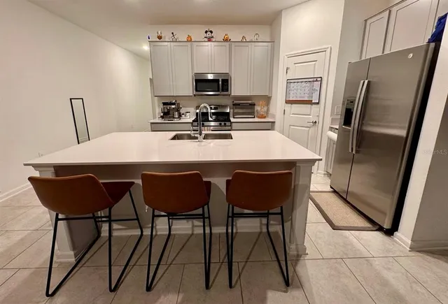 a kitchen with stainless steel appliances a table chairs in it and wooden floors