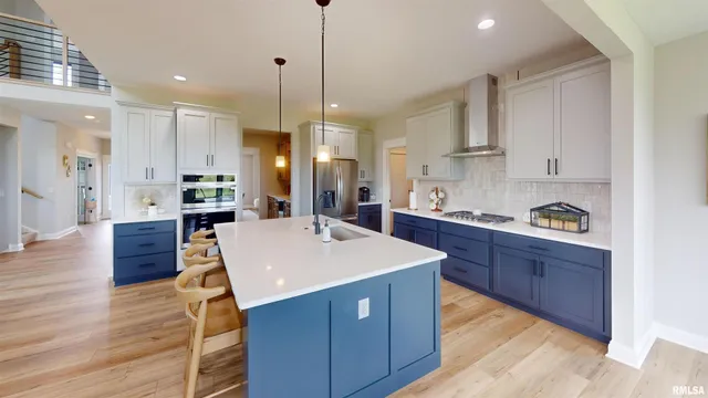 a large kitchen with stainless steel appliances kitchen island granite countertop wooden cabinets a refrigerator a sink a stove and a wooden floors