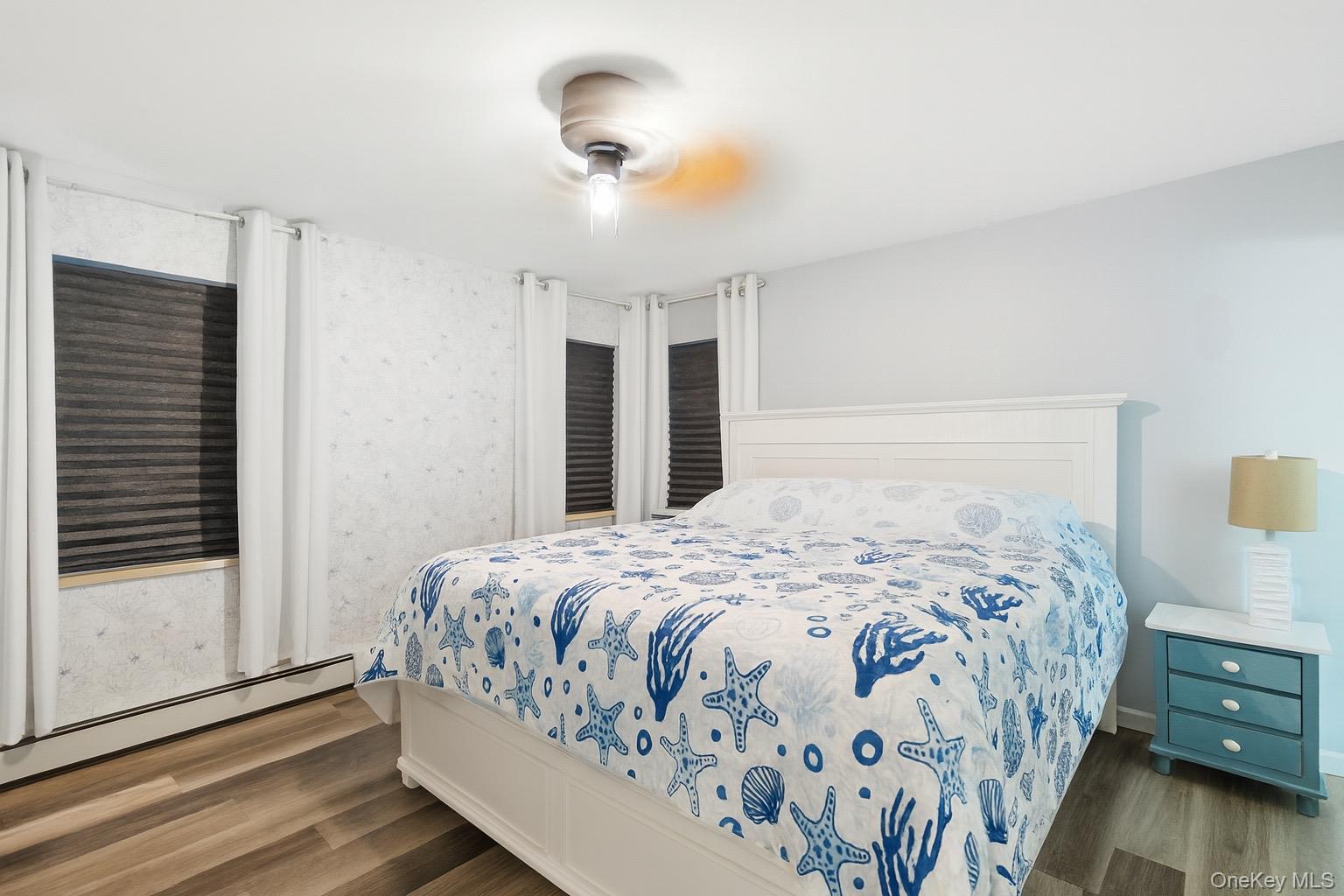 1-76 Beach 101st Street, Unit 4A Queens, NY 11694 - Photo 7 of 16 Bedroom featuring dark wood finished floors, a baseboard heating unit, and a ceiling fan