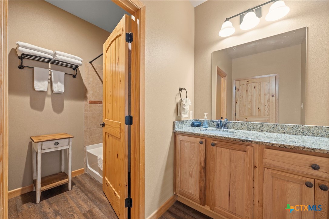1554 Gruene Road, Unit A10 New Braunfels, TX 78130 - Photo 15 of 32 a bathroom with a granite countertop sink a mirror and a shower
