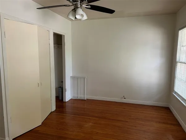an empty room with wooden floor fan and windows