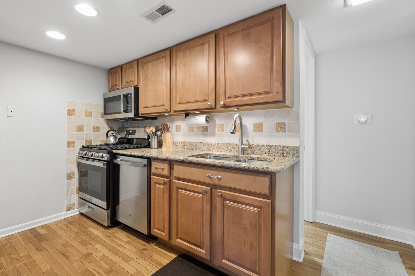 1122 West Altgeld Street, Unit 12 Chicago, IL 60614 - Photo 9 of 20 a kitchen with stainless steel appliances granite countertop a stove a sink and a microwave