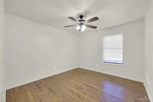 a view of an empty room with a window and wooden floor