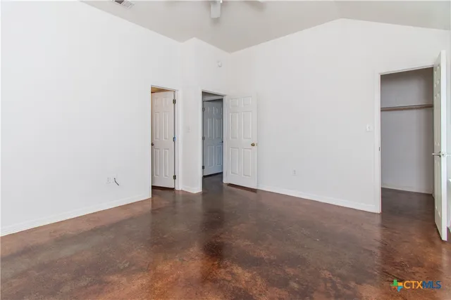 an empty room with closet and a chandelier fan