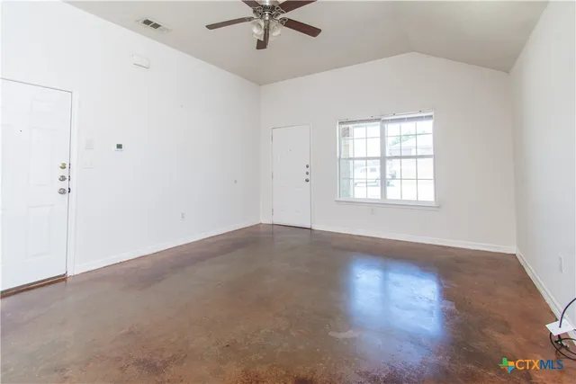 an empty room with wooden floor fan and windows