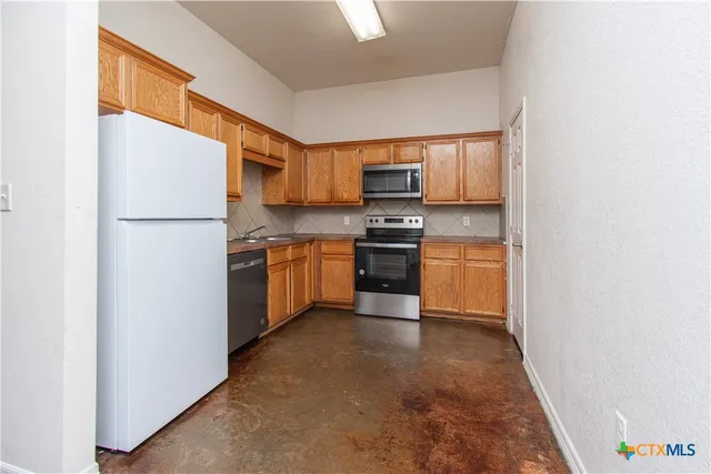 a kitchen with stainless steel appliances granite countertop a stove a sink refrigerator and a microwave