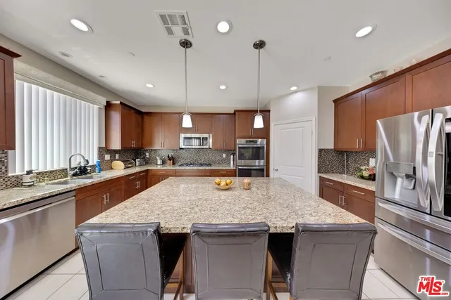 a kitchen with stainless steel appliances granite countertop a sink a stove and refrigerator