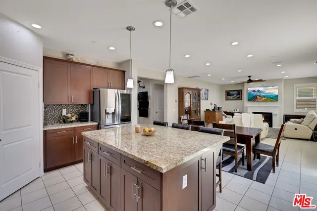 a kitchen with stainless steel appliances granite countertop a table chairs sink and cabinets
