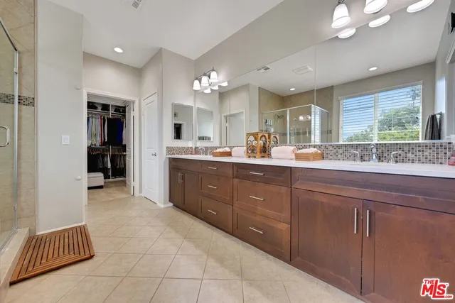 a large bathroom with a double vanity sink a toilet a mirror and shower