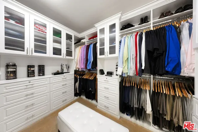 a view of walk in closet with clothes and shoes