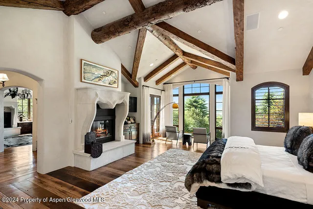 a spacious bedroom with a bed a mirror and lamp on table