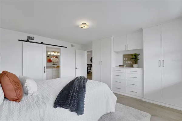 a bedroom with a bed a dresser and cabinets
