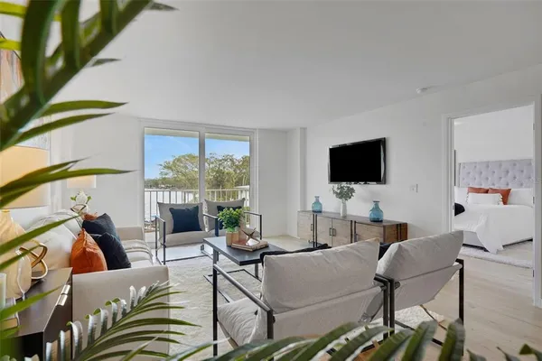 a living room with furniture a flat screen tv and a floor to ceiling window
