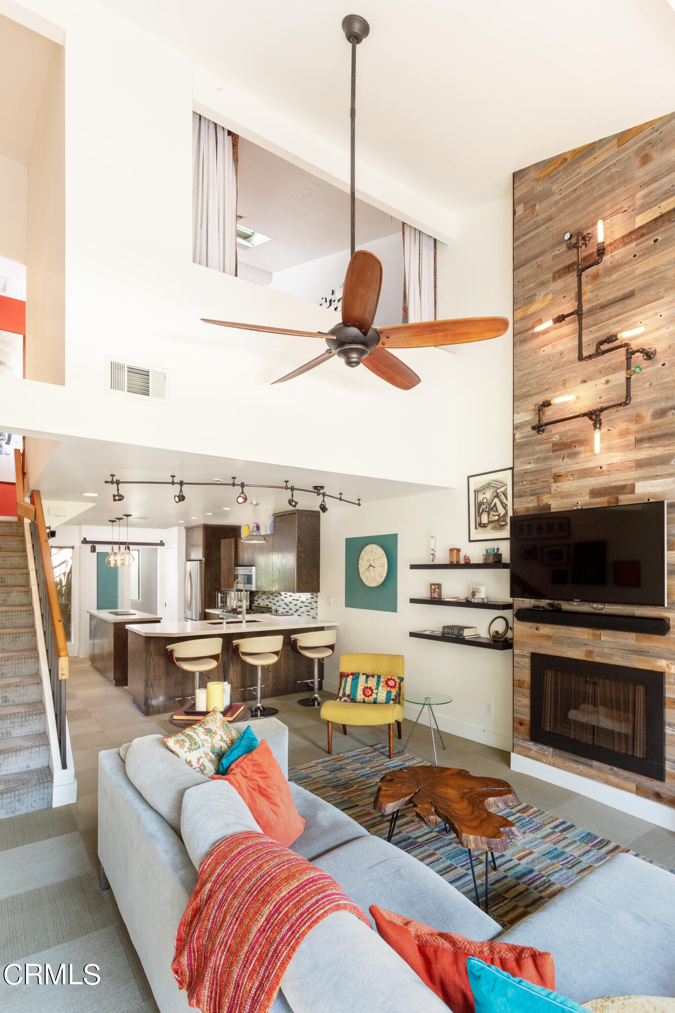 a living room with stainless steel appliances furniture and a flat screen tv
