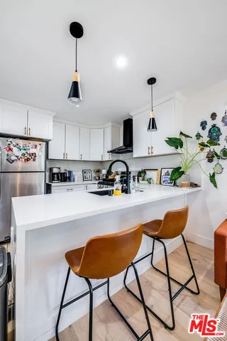 a living room with stainless steel appliances furniture a rug and a chandelier