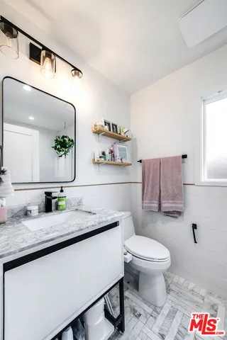 a bathroom with a granite countertop toilet sink and mirror