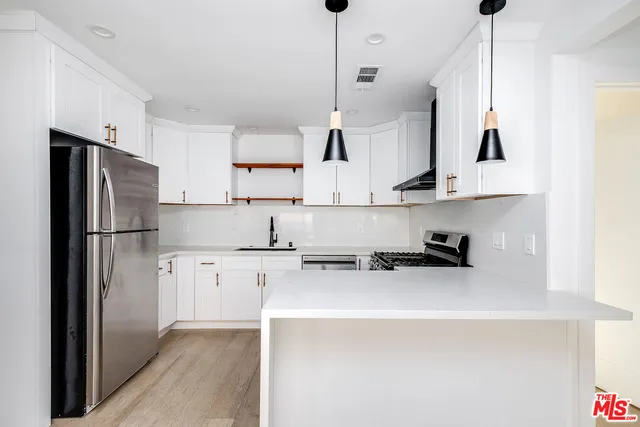 a kitchen with stainless steel appliances a refrigerator a stove a sink and white cabinets