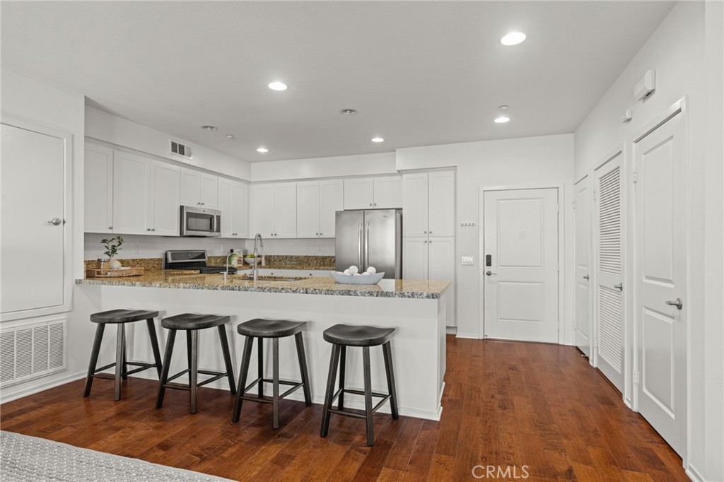 5540 Strand, Unit 201 Hawthorne, CA 90250 - Photo 5 of 31 a kitchen with stainless steel appliances granite countertop a stove a sink a refrigerator and white cabinets with wooden floor