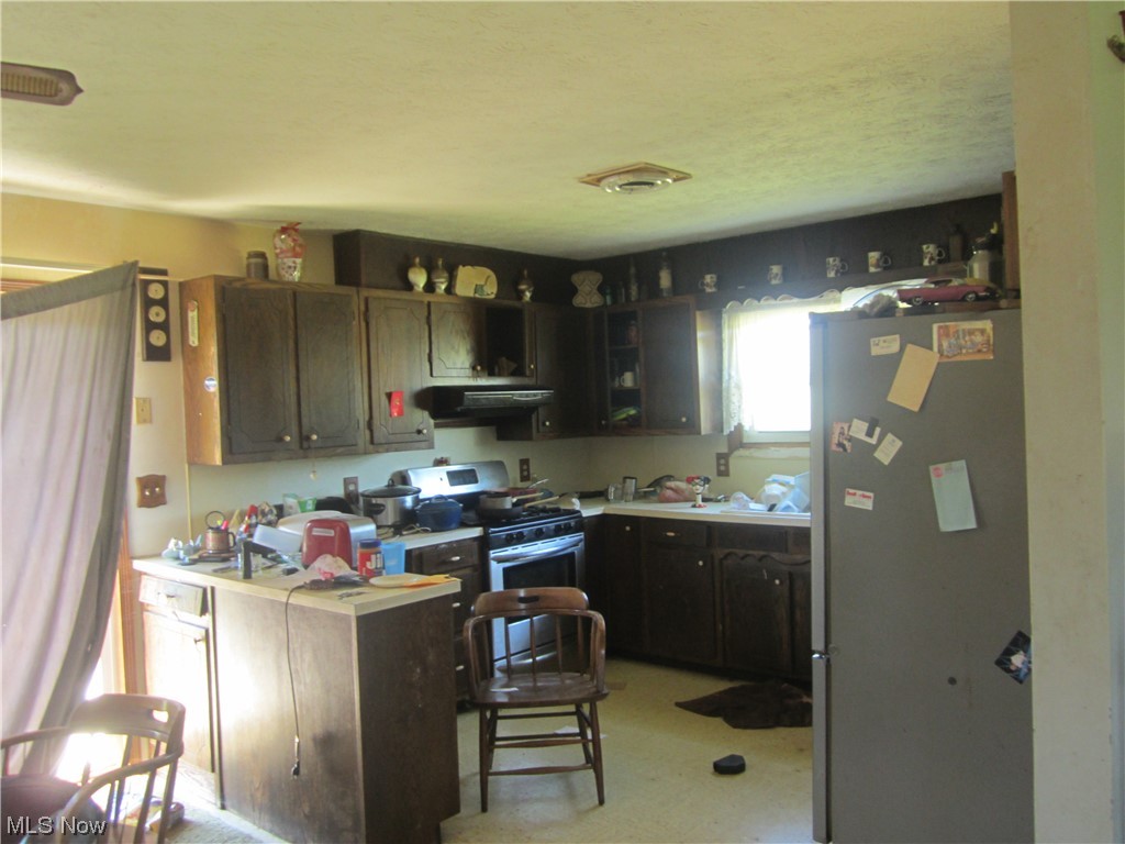 2191 Hoover Road Waterford, OH 45786 - Photo 26 of 30 Kitchen with extractor fan, dark brown cabinetry, light countertops, white fridge, and range with gas stovetop