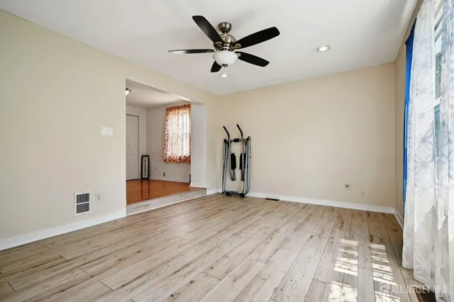 an empty room with wooden floor and a ceiling fan